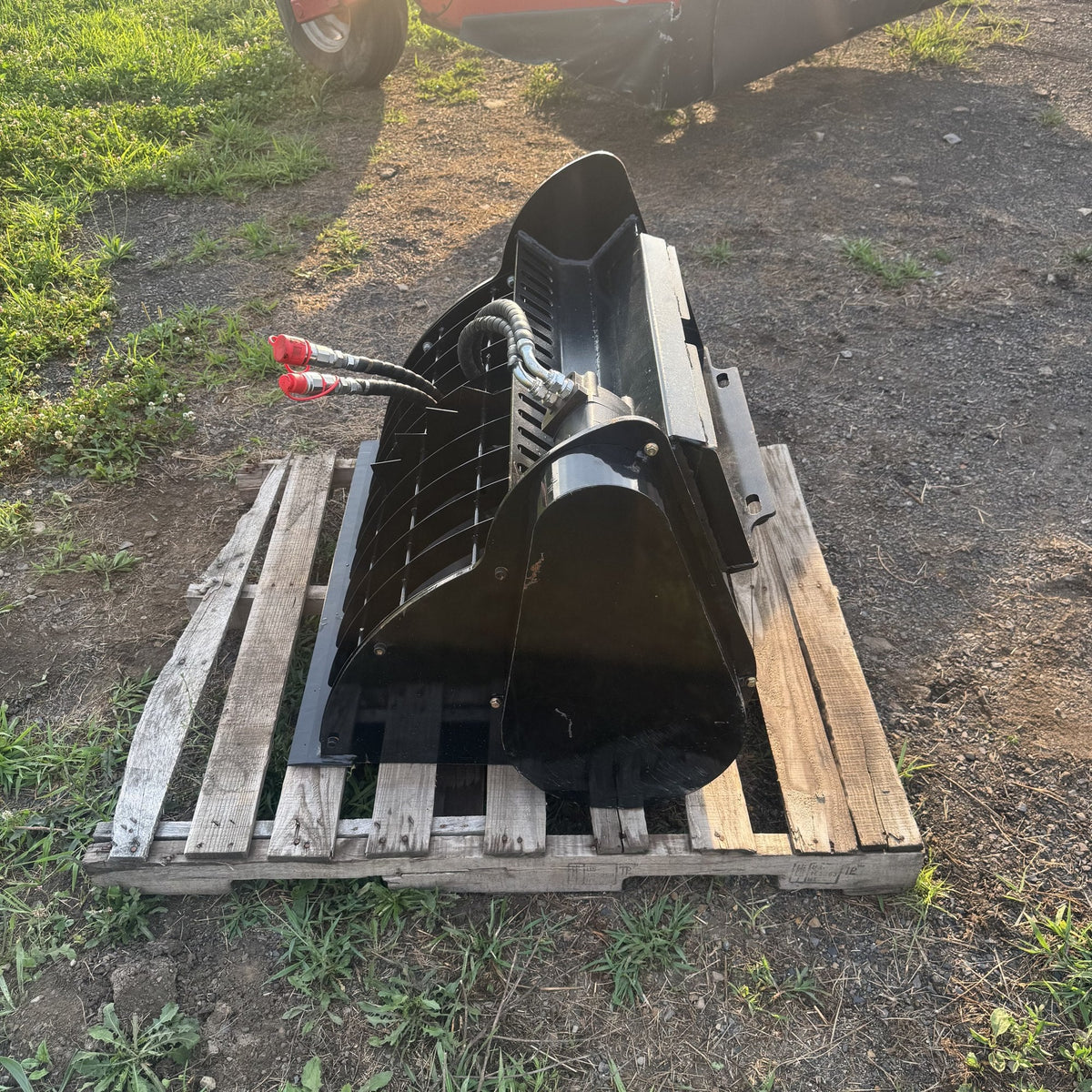 Mixer bucket viewed from the front with hydraulic couplers and pour chute